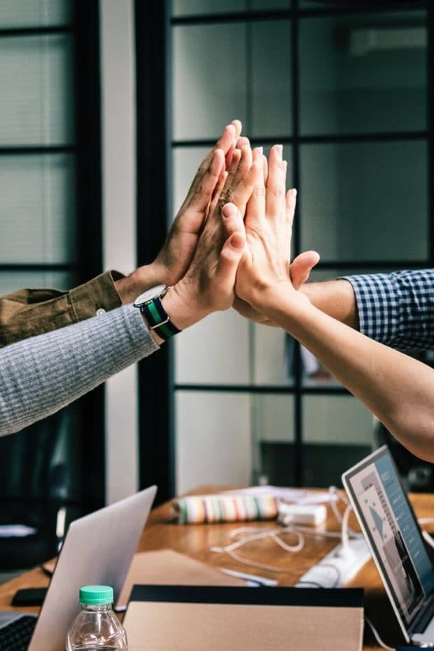 Team members celebrating a group high-five in a collaborative office workspace